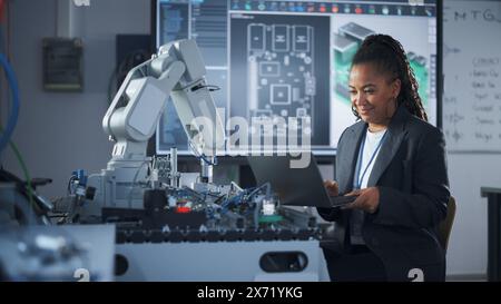 Black Developer fonctionne avec ordinateur portable, écriture de code pour bras de robot. Laboratoire de recherche en informatique avec des spécialistes travaillant. Concept High-Tech Science and Programming at Start Up Lab. Banque D'Images