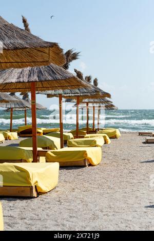 Chaises de plage recouvertes de couvertures jaunes près de la plage, sur fond de mer. Faible profondeur de champ, mise au point sélective sur les chaises longues. Banque D'Images