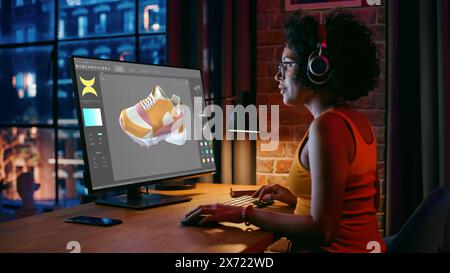 Directeur artistique féminin noir examinant le modèle 3D de chaussure tout en travaillant à l'ordinateur de bureau à la maison. Artiste Girl Making visualisation au programme spécial. Concepteur graphique au bureau à domicile concept. Banque D'Images