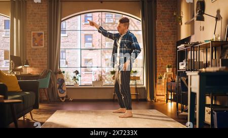 Portrait de beau jeune homme élégant dansant dans des vêtements décontractés, s'amuser à la maison dans Loft Apartment. Enregistrement de vidéos virales drôles pour les médias sociaux. Banque D'Images
