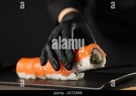 Chef en gants faisant des rouleaux de sushi à la table grise, gros plan Banque D'Images