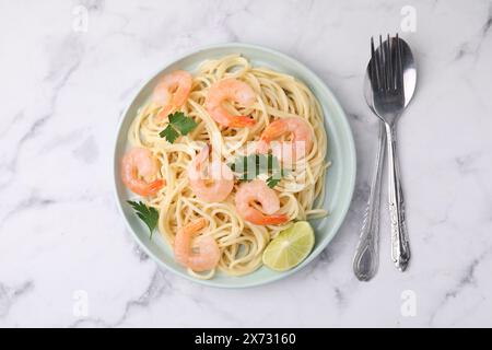 Savoureux spaghetti aux crevettes, citron vert et persil servis sur une table en marbre blanc, vue de dessus Banque D'Images