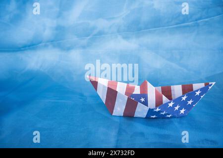 Bateau en papier avec drapeau américain sur fond bleu. Concept Columbus Day. Banque D'Images