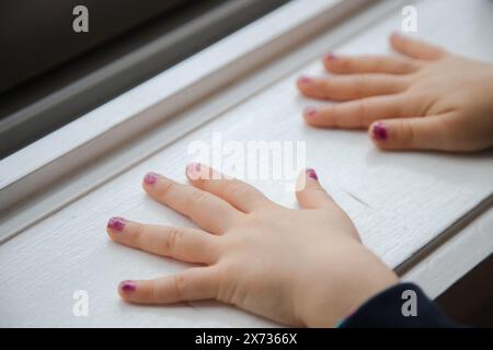 Les mains du petit enfant après avoir peint leurs ongles avec du vernis à ongles coloré. Fermez et copiez l'espace. Banque D'Images