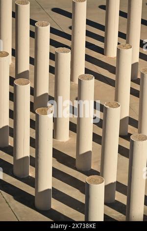 Vue aérienne de piliers cylindriques en béton projetant de longues ombres sur une surface plane, créant un motif géométrique saisissant avec jeu de lumière et d'ombre Banque D'Images