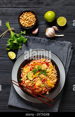 pad thai, phad thai, nouilles de riz sautées avec crevettes, cacahuètes, œufs brouillés, germes de haricots, oignons de printemps, poivron rouge et sauce dans un bol noir, ve Banque D'Images