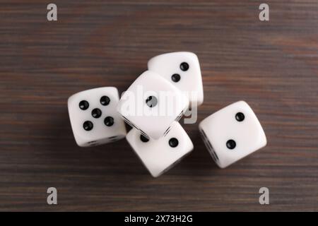 Beaucoup de dés de jeu blanc sur la table en bois, vue de dessus Banque D'Images