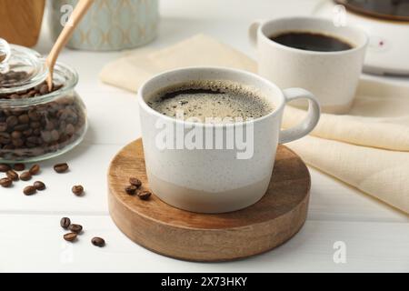 Café aromatique dans la tasse et les haricots sur la table en bois blanc Banque D'Images