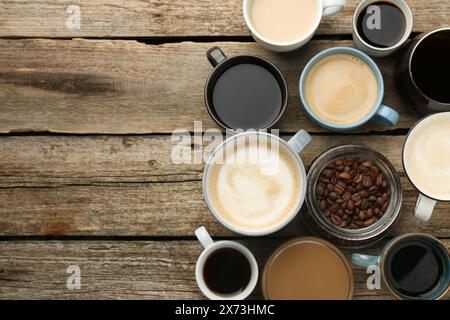 Différentes boissons de café dans des tasses et des haricots sur la table en bois, plat. Espace pour le texte Banque D'Images