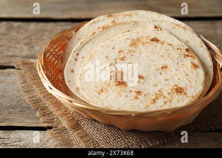 Tortillas maison savoureuses dans un panier en osier sur une table en bois Banque D'Images