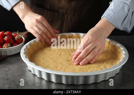 Pâte brisée. Femme faisant une tarte à la table grise, gros plan Banque D'Images