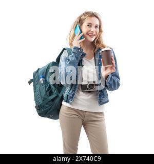 Heureuse jeune femme voyageuse touristique avec smartphone, tenant une tasse de papier et buvant du café, portant un sac à dos sur les épaules, isolé sur backgrou blanc Banque D'Images