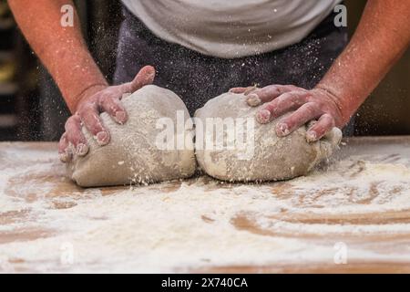 Un boulanger pétrit la pâte à pain dans la boulangerie. Banque D'Images