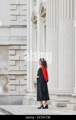 Une étudiante diplômée, en tenue académique, de l'Université de Cambridge, en Angleterre, célèbre son succès académique sur les marches de la Chambre du Sénat, vendredi 17 mai 2024. Banque D'Images