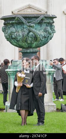 Une étudiante diplômée, en tenue académique, de l’Université de Cambridge, en Angleterre, célèbre sa réussite académique avec son amie sur la pelouse de la Chambre du Sénat, devant l’urne géante graeco, le vendredi 17 mai 2024. Banque D'Images