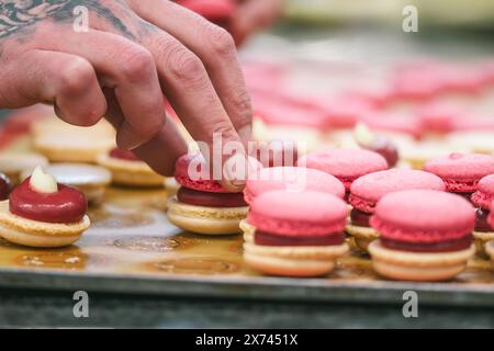 Mains de confiseur finissant les macarons roses Banque D'Images