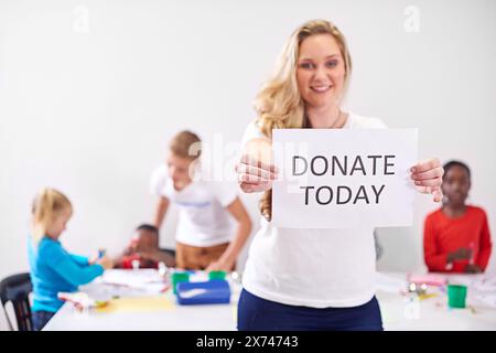 Faites un don aujourd'hui, portrait ou femme avec du papier pour don, aide ou signe pour le service communautaire ou la société. Charité, sourire ou volontariat heureux avec affiche Banque D'Images