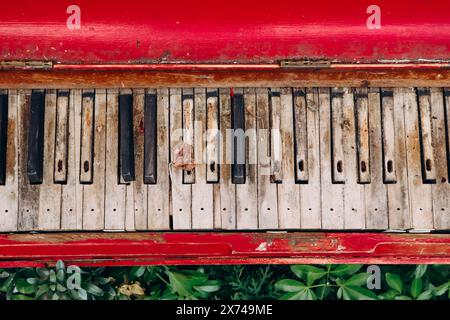 Gros plan d'un vieux piano rouge avec des touches minables dans la rue de Londres Banque D'Images