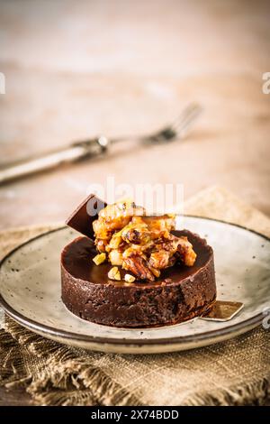 Tartelette au chocolat avec garniture de noix caramélisées, amandes et pistaches, verticale avec espace de copie. Banque D'Images