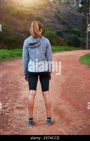 Fitness, nature et trail avec femme coureuse en plein air de dos pour le début de l'entraînement cardio matinal. Exercice, forêt ou montagne et athlète de course dans Banque D'Images