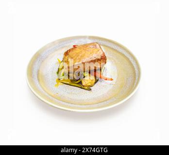Une tranche de saumon cuite avec des légumes dans une élégante assiette sur fond blanc Banque D'Images