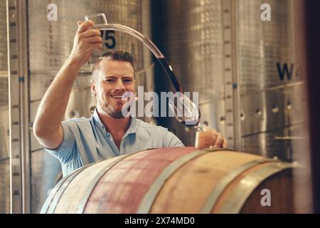 Homme, heureux et viticulteur avec couler dans le verre comme gestionnaire pour la dégustation, le processus et la production. Portrait, cave et sourire en toute confiance avec le produit Banque D'Images