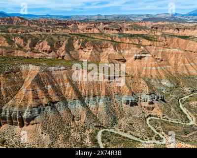 Majestueux rochers rouges et canyons avec des routes sinueuses dans un vaste paysage désertique, vue aérienne, Los Coloraos, Grand Canyon d'Andalousie, désert de Gorafe Banque D'Images