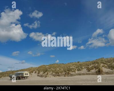 Vue sur la plage avec dunes herbeuses et une maison sous un ciel nuageux, nuages sur la plage avec des dunes au bord de la mer, hollum, ameland, pays-bas Banque D'Images