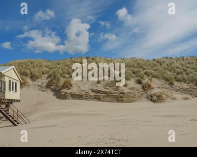 Vue d'une dune de sable herbeux avec une petite maison surélevée et un ciel bleu, nuages sur la plage avec des dunes au bord de la mer, hollum, ameland, pays-bas Banque D'Images