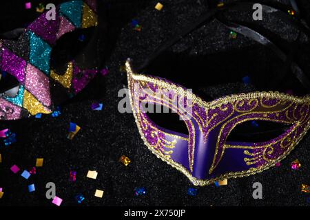Masque de mascarade avec confetties sur fond noir. Banque D'Images