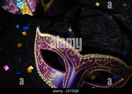 Masque de mascarade avec confetties sur fond noir. Banque D'Images