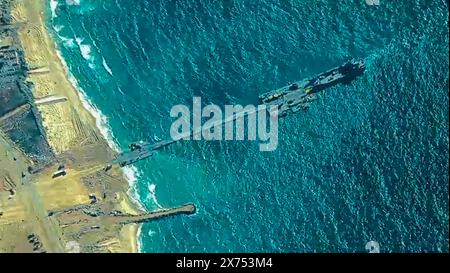 Mer Méditerranée, Israël. 16 mai 2024. Une image satellite montrant l'U. S Navy Trident Floating Pier est positionné au large de la côte méditerranéenne avec une chaussée flottante à la plage pour le mouvement des camions, le 16 mai 2024, à Gaza, territoire palestinien. Le quai flottant sera utilisé pour acheminer l'aide humanitaire directement des navires vers la terre pour le peuple palestinien à Gaza. Crédit : CENTCOM/US Army photo/Alamy Live News Banque D'Images