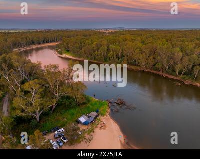 Vue aérienne des campings sur une rive de rivière sablonneuse sous un ciel de coucher de soleil coloré sur la rivière Murray près de Cobram dans le Victoria, Australie Banque D'Images