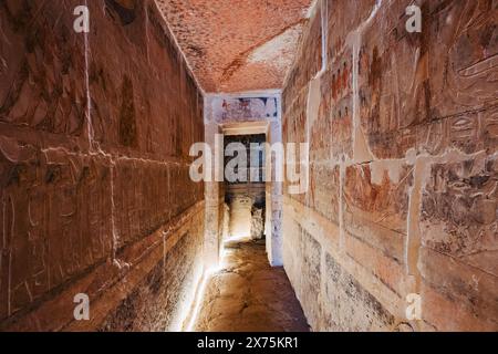 Couloir éclairé dans un tombeau mastaba Saqqara avec des reliefs peints de l'ancien Empire sur les deux murs, menant à une chambre intérieure pleine de décoration symbolique Banque D'Images