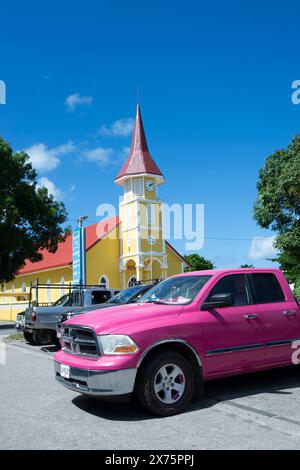 Grosse voiture rose devant une église jaune, Vaitape, île de Bora Bora, îles de la Société, Polynésie française Banque D'Images