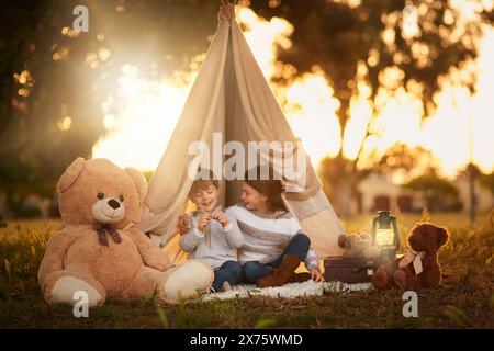 Tipi, enfants et plaisir dans la tente de jardin en plein air dans la nature pour le camping, le jeu et l'aventure avec la lumière du soleil. Tissu, lumière et fantaisie maison pour les enfants dans Banque D'Images