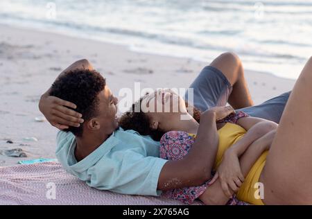 À la plage, couple diversifié riant, femme tenant la main de l'homme Banque D'Images