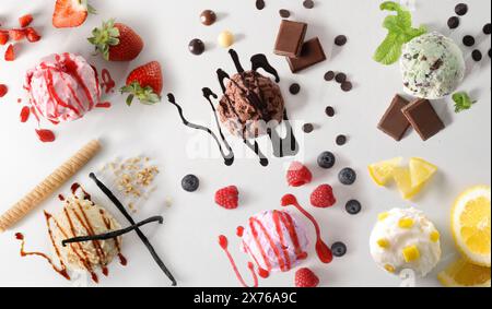 Assortiment de boules de crème glacée décorées de fruits et sirops sur table blanche. Vue de dessus. Banque D'Images