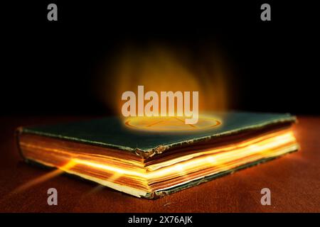 Livre de sorts fermé avec des rayons de lumière sortant des pages et une lueur flamboyante éclatant du pentacle inversé sur sa couverture. Banque D'Images
