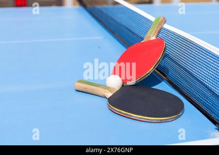 Deux raquettes de tennis de table ou de ping-pong et balle sur la table bleue avec filet Banque D'Images