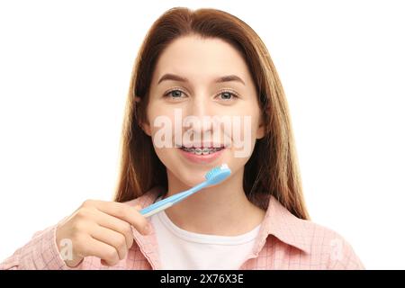 Femme souriante avec des appareils dentaires nettoyant les dents sur fond blanc Banque D'Images