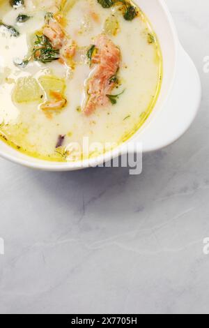 Soupe crémeuse finlandaise avec saumon, pommes de terre, oignons et carottes dans un bol sur la table en bois, foyer sélectif Banque D'Images