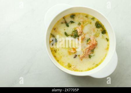 Soupe crémeuse finlandaise avec saumon, pommes de terre, oignons et carottes dans un bol sur la table en bois, foyer sélectif Banque D'Images