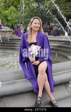 Après la cérémonie de remise des diplômes de NYU 2024, une belle femme asiatique américaine pose pour des photos tout en tenant des fleurs. Dans Washington Square Park à Manhattan Banque D'Images