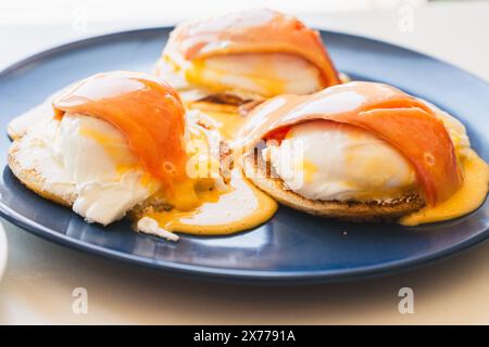 Griller avec les œufs pochés, le saumon et la sauce hollandaise sur une assiette bleue. Concept de petit déjeuner sain. Photo de haute qualité Banque D'Images