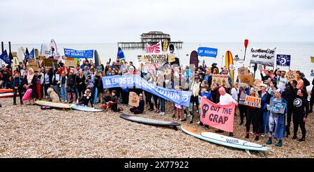 Brighton UK 18 mai 2024 - les Surfers contre les eaux usées protestent aujourd'hui par Brighton West Pier alors que des centaines de planchistes et de nageurs prennent la mer faisant campagne pour que les compagnies d'eau cessent de pomper les eaux usées dans la mer et les voies navigables autour de la Grande-Bretagne . Crédit Simon Dack / Alamy Live News Banque D'Images