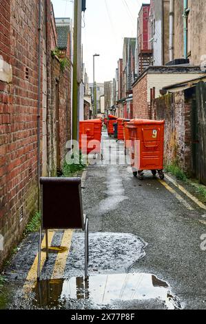 Rangée de bennes de couleur orange et chaise indésirable dans la ruelle arrière Banque D'Images