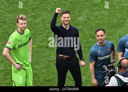 Leverkusen, Allemagne. 18 mai 2024. Football, Bundesliga, Bayer Leverkusen - FC Augsburg, Journée 34, BayArena, entraîneur Xabi Alonso (M) encourage les fans avant de remettre le trophée du championnat. Sur la gauche se trouve le gardien de but de Leverkusen, Lukas Hradecky. NOTE IMPORTANTE : conformément aux règlements de la DFL German Football League et de la DFB German Football Association, il est interdit d'exploiter ou de faire exploiter des photographies prises dans le stade et/ou du match sous forme d'images séquentielles et/ou de séries de photos de type vidéo. Crédit : David Inderlied/dpa/Alamy Live News Banque D'Images