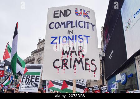 Londres, Royaume-Uni. 18 mai 2024. Un manifestant pro-palestinien tient une pancarte « mettre fin à la complicité du Royaume-Uni dans les crimes de guerre sionistes » à Piccadilly Circus. Des milliers de personnes ont défilé en solidarité avec la Palestine à l’occasion du 76e anniversaire de la Nakba, alors qu’Israël poursuit ses attaques contre Gaza. Crédit : Vuk Valcic/Alamy Live News Banque D'Images