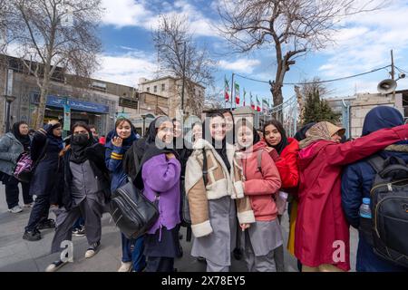 Téhéran, Iran - 7 mars 2024 : un groupe d'étudiantes locales quitte l'école dans l'après-midi. Les arbres et les drapeaux sont vus en milieu urbain. Banque D'Images